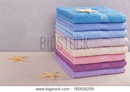 Stack of colorful bath towels with sea stars on light background. Pastel colors cotton or bamboo towels. Hygiene fabricspa and textile concept