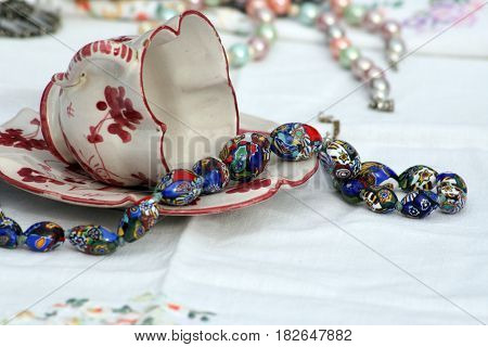 Antique blue bead necklace spilling from antique teacup