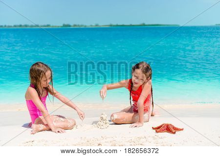 Little girls having fun at tropical beach during summer vacation playing together at shallow water