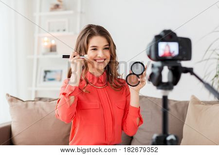blogging, technology, videoblog, makeup and people concept - happy smiling woman or beauty blogger with bronzer, brush and camera recording tutorial video at home