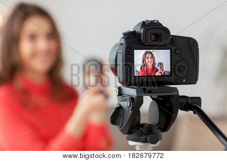 blogging, technology, videoblog, makeup and people concept - happy smiling woman or beauty blogger with bronzer, brush and camera recording tutorial video at home