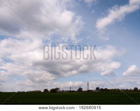 A Shot Of Far Away Field Green And With Several Lined Up Electrical Wire Metal Frames Standing And W