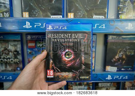 Bratislava, Slovakia, circa april 2017: Man holding Resident Evil Revelations 2 videogame on Sony Playstation 4 console in store