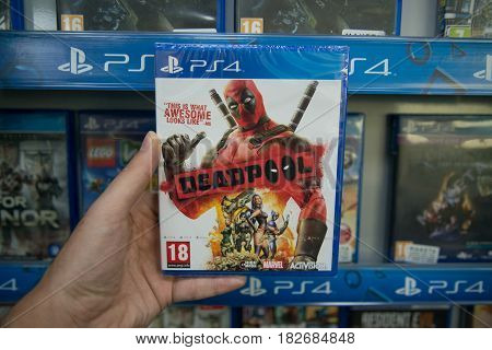 Bratislava, Slovakia, circa april 2017: Man holding Deadpool videogame on Sony Playstation 4 console in store