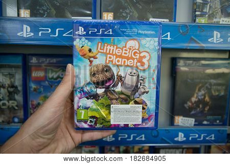 Bratislava, Slovakia, circa april 2017: Man holding Little Big Planet 3 videogame on Sony Playstation 4 console in store