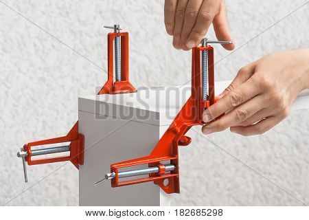 hand of carpenter installing clamp before furniture assembling