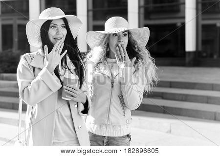 Black and white photo of cheerful girlfriends in hats