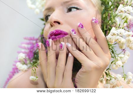 Beautiful woman with design of summer pink flower Astilbe on the lips and on the fingers.The nail design.White pink manicure and makeup.