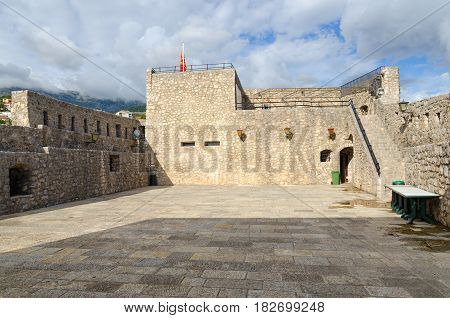 HERCEG NOVI MONTENEGRO - SEPTEMBER 25 2015: Unknown tourist sits on ramparts of Sea Fortress (Forte Mare) in Old Town Herceg Novi Montenegro
