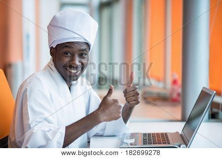 Sudanese business man in traditional outfit using mobile phone in office.
