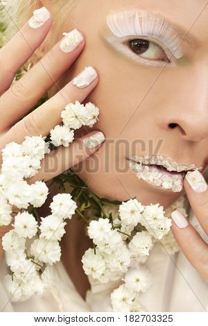 Summer white makeup and manicure with design on nails of baby's breath flowers closeup.