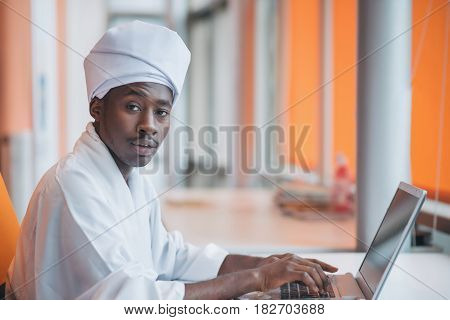 Sudanese business man in traditional outfit using mobile phone in office.