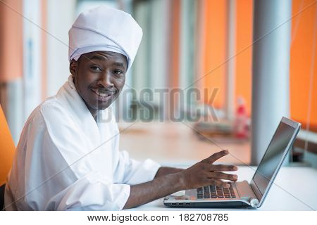 Sudanese business man in traditional outfit using mobile phone in office.