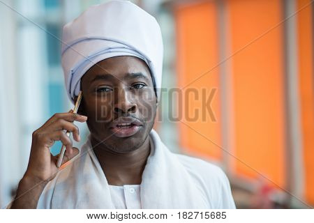 Sudanese business man in traditional outfit using mobile phone in office.