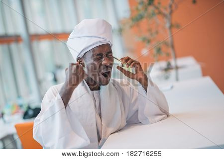 Sudanese business man in traditional outfit using mobile phone in office.