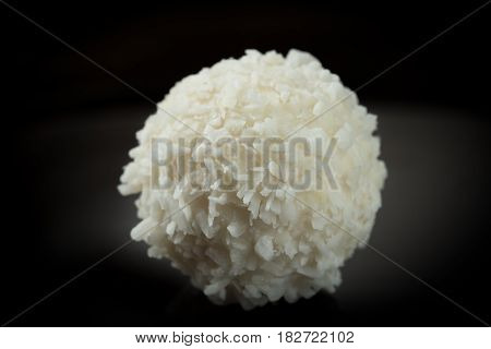 One sweet coconut candy isolated on black background, close-up