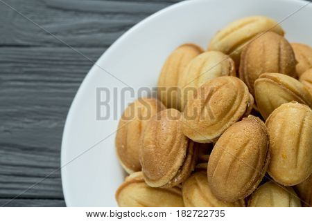 Pile of cookies with condenced boiled milk on white plate on wooden background