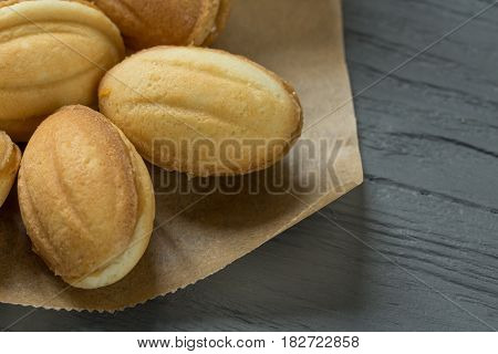 Cookies with boiled condenced milk on cooking paper with wooden background, close-up