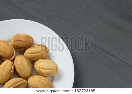 Homemade cookies with condenced milk on a white plate in a corner, wooden background