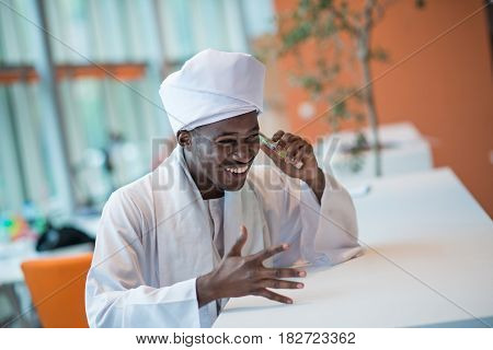 Sudanese business man in traditional outfit using mobile phone in office.