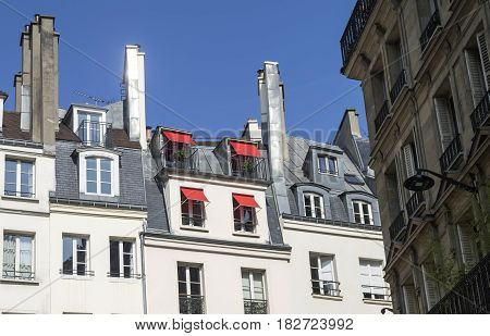 Red sun awnings on the windows of the attic. Paris France.