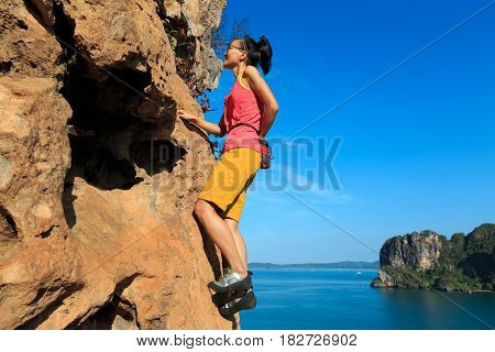 free solo woman rock climber climbing at seaside cliff