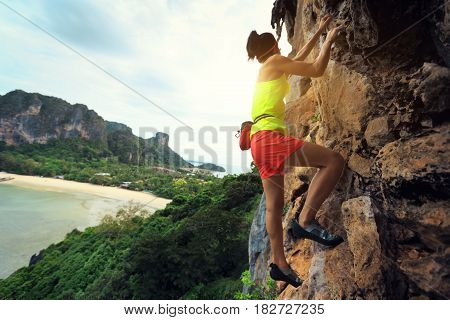 free solo woman rock climber climbing at seaside cliff