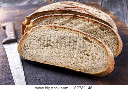 Freshly backed Farmhouse Bread sliced as close-up on an old burnt cutting board