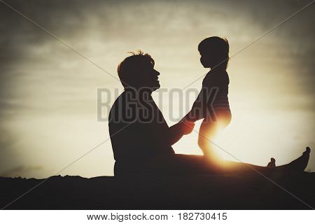silhouette of grandmother and little granddaughter play at sunset beach