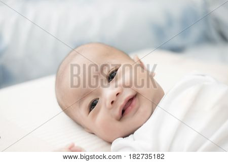 Portrait of cute 3 months Asian baby boy lying down on a blanket and smile.