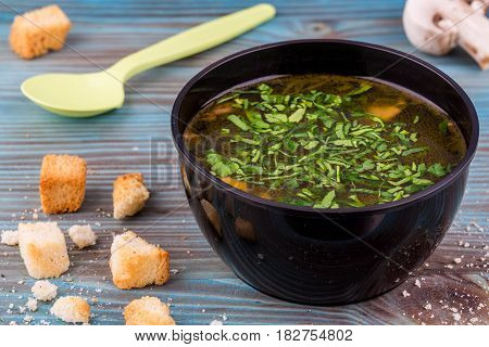 Mushroom soup with toasts and greens, is served in plastic ware