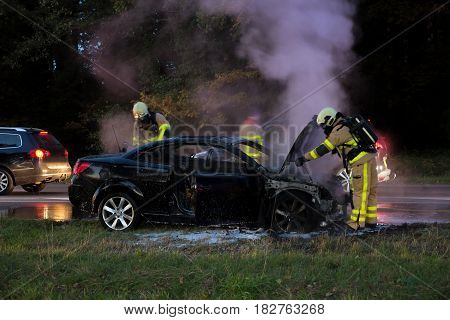 Firefighters near a burned out car wreck.