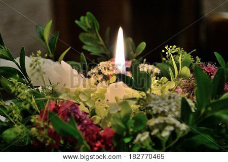 Romantic candlelight on a flower arrangement - closeup