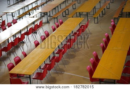 table with red chairs in a wide lunch room in a school