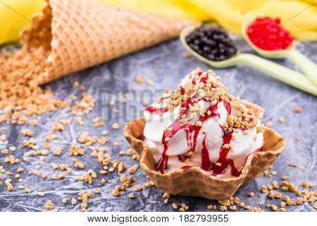An ice cream basket with raspberry jam, sprinkled shredded nuts
