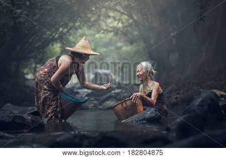 Old Asian woman working in creek, countryside of Thailand