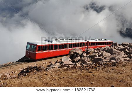 Tram carries tourists up the steep incline of Pikes Peak through the clouds