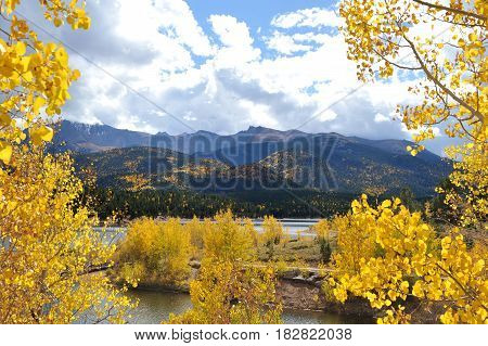 A view of Pikes Peak crested with snow and surrounded by storm clouds as seen from below behind Cyrstal Resevoir.