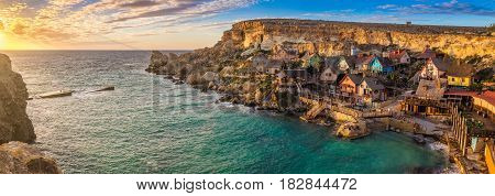 Il-Mellieha Malta - Sunset at the famous Popeye Village at Anchor Bay on a panoramic image