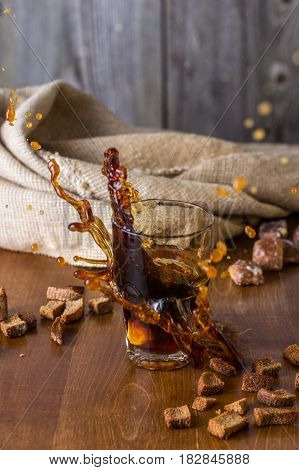 Traditional Russian drink kvass from bread rye malt sugar and water. Kvass in a glass on a dark wooden background. Splash