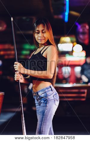 Young beautiful girl in a billiard club with cue stick posing