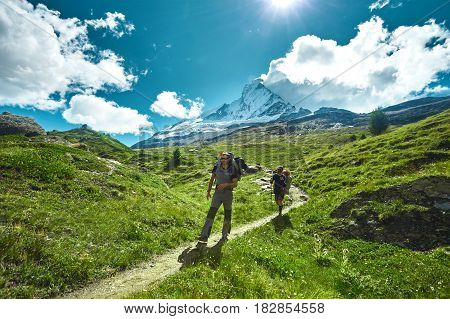 hikers with backpacks on the trail in the Apls mountains. Trek near Matterhorn mount