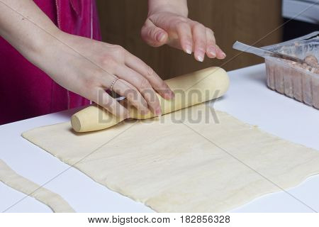 Stages Of Preparation Of Meat Glomeruli. A Woman Rolls Out The Dough. Next To The Table Is A Stuffin