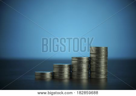 pile of coins money on dark wood and soft blue background
