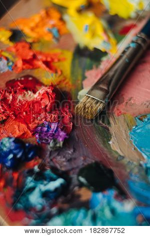 color palette with fresh paint and brush on wood table