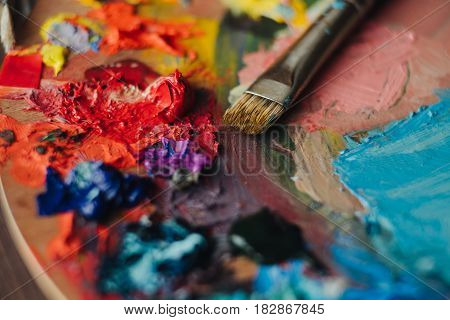 color palette with fresh paint and brush on wood table