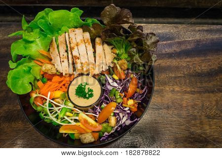 The top view of chicken salad with vegetable and tomato on dark wooden table