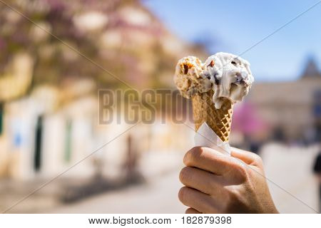 Close up focus of female hand holding melting delicious ice cream in summer Italy