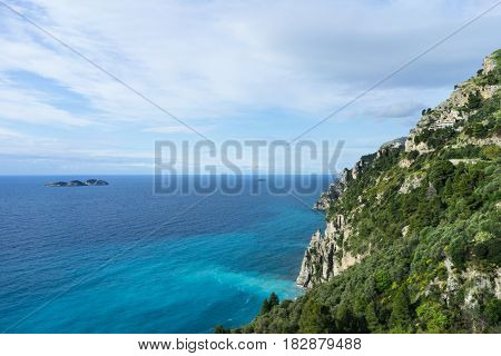 The rural coastal hills / mountains blue sky white clouds & green grass as seen from Highway with sun shine in southern Italy Positano