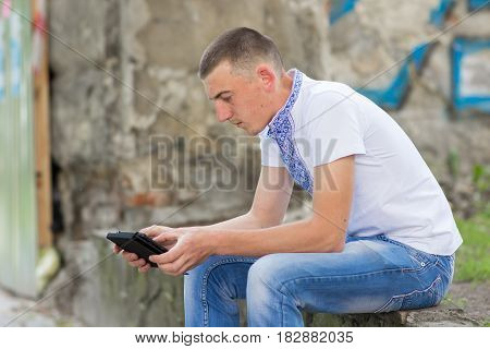 young Ukrainian with tablet sitting on the street